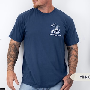 May include: A navy blue t-shirt with a white graphic that says "Best Dad By Par" with a golf club and golf ball design.