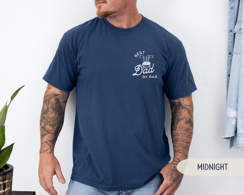 May include: A navy blue t-shirt with a white graphic that says "Best Dad By Par" with a golf club and golf ball design.