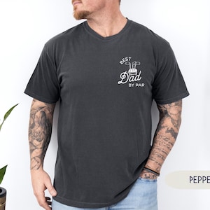 May include: A dark gray t-shirt with a white graphic that says "Best Dad By Par" and a golf club design.