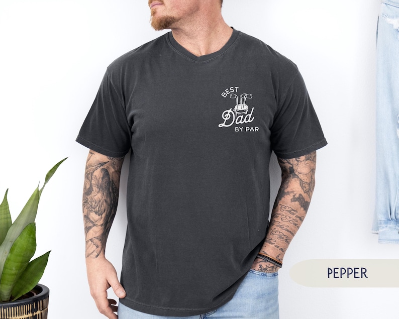 May include: A dark gray t-shirt with a white graphic that says "Best Dad By Par" and a golf club design.