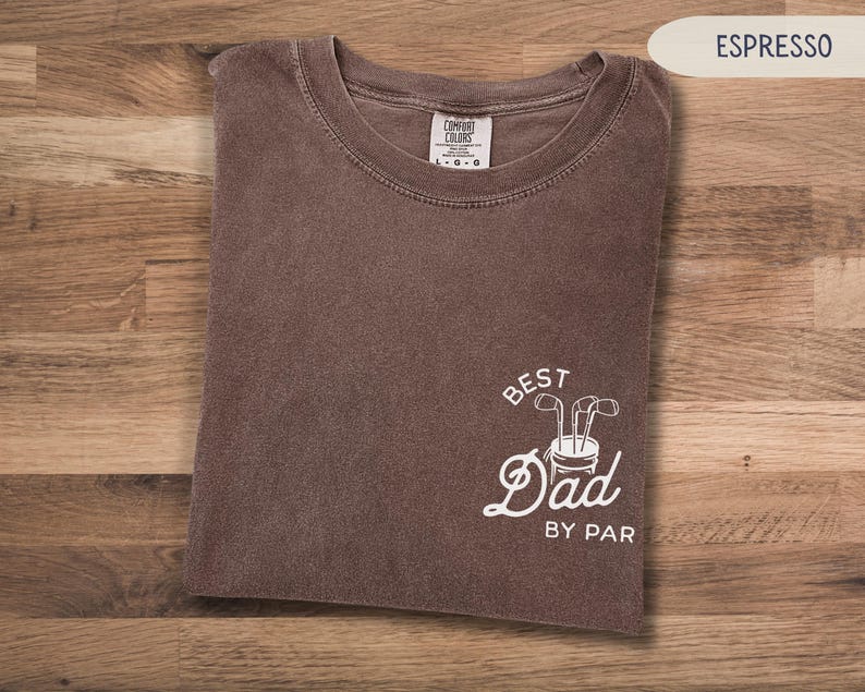 May include: A brown t-shirt with the text "Best Dad By Par" in white. The text is accompanied by a graphic of a golf bag with golf clubs.