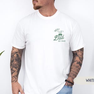 May include: White t-shirt with a green graphic that says "Best Dad By Par" with a golf club and golf ball design.