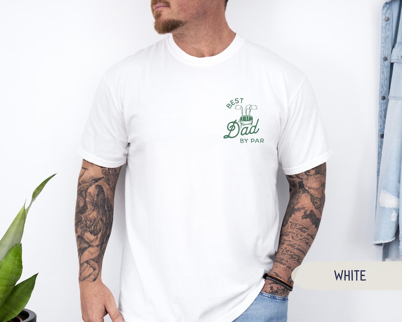 May include: White t-shirt with a green graphic that says "Best Dad By Par" with a golf club and golf ball design.