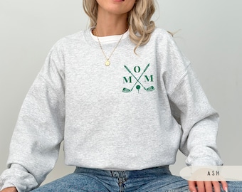 Puede incluir: Sudadera gris con un diseño de palo de golf verde y el texto "MOM" en la parte delantera.