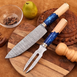 May include: A set of two kitchen knives with blue and wood handles. The knives have a Damascus steel blade and are displayed on a wooden cutting board.