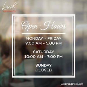 May include: White framed sign with the text "Open Hours". The sign displays the business hours: Monday to Friday 9:00 AM to 5:00 PM, Saturday 10:00 AM to 7:00 PM, and Sunday closed. The Lucid Printing Co. logo is at the top.