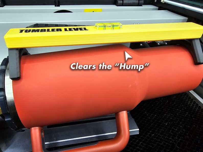 K&ouml;nnte beinhalten: Eine gelbe Wasserwaage mit dem Text "TUMBLER LEVEL" ist an einem roten Becher befestigt. Die Wasserwaage dient dazu, sicherzustellen, dass der Becher waagerecht ist und die "Hump" der Maschine &uuml;berwindet.
