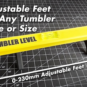 K&ouml;nnte beinhalten: Eine gelbe Wasserwaage mit verstellbaren F&uuml;&szlig;en, beschriftet mit "Tumbler Level". Die F&uuml;&szlig;e sind von 0 bis 230 mm verstellbar.