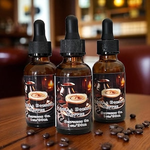 May include: Three brown glass bottles with black droppers, labeled "Vanilla Bourbon Coffee Diffusion Oil 1 oz/30ml." Each bottle features a label with a coffee cup design. Coffee beans are scattered on the wooden surface.