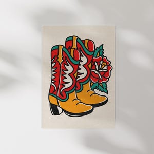 May include: Illustration of a pair of cowboy boots in red, yellow, and white with a red rose and green leaves. The boots have a classic design with decorative stitching and a black heel. The artwork is on a cream-colored background.