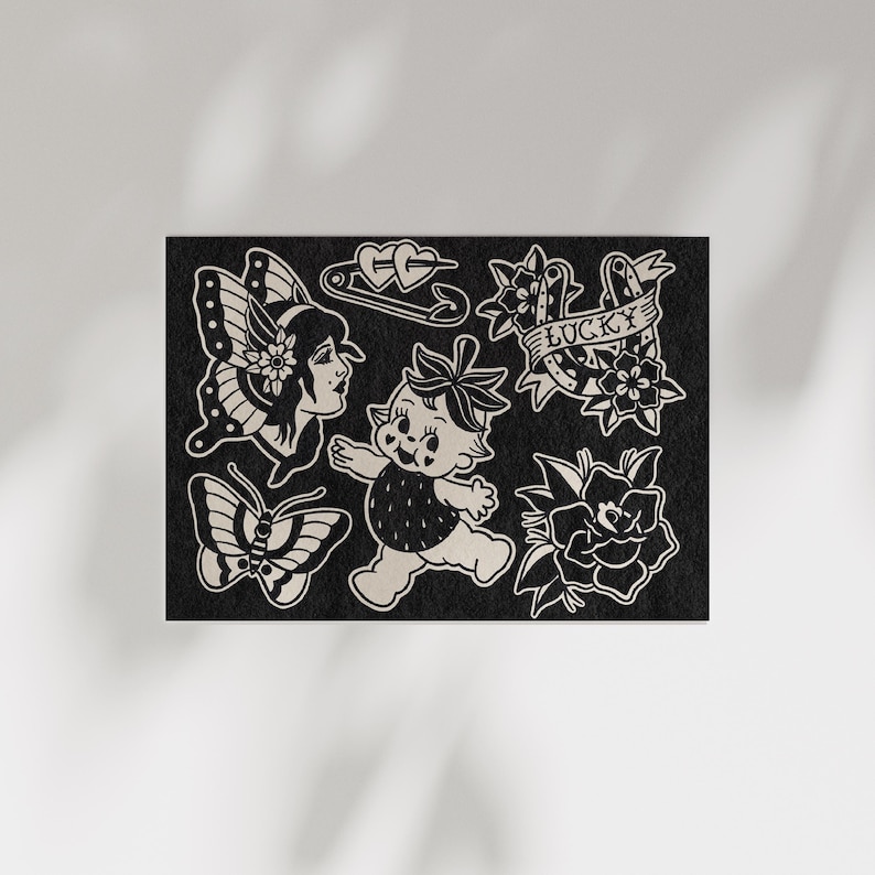 May include: Black and white tattoo flash sheet featuring various designs. Includes a butterfly, a woman with butterfly wings, a baby with a strawberry head, a safety pin with hearts, a banner that says "Lucky", and flowers.