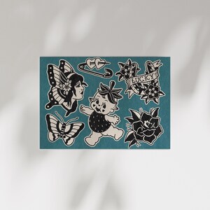 May include: A collection of black and white traditional tattoo flash art on a teal background. Designs include a butterfly, a woman's face, a baby, a safety pin with hearts, a banner that says "LUCKY", and flowers.