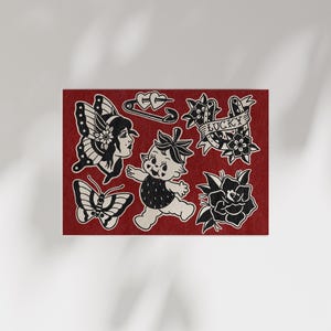 May include: A red card featuring black and white traditional tattoo designs. The designs include a butterfly, a woman's face, a baby, a safety pin with hearts, a banner that says "Lucky", and roses.