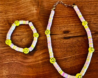 A pink and yellow clay bead matching chocker and bracelet with smiley faces