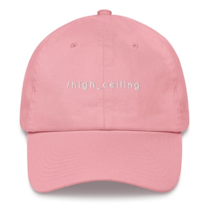Puede incluir: Una gorra de béisbol rosa con el texto "/high_ceiling" bordado en blanco en la parte delantera.