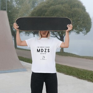 K&ouml;nnte beinhalten: Eine Person tr&auml;gt ein wei&szlig;es T-Shirt mit dem Text "I'm single cause MDZS exists" und einer Schwarzwei&szlig;illustration eines Charakters. Die Person h&auml;lt ein Skateboard &uuml;ber ihrem Kopf.