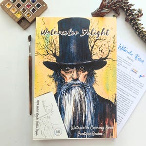 以下が含まれることがあります： 「Watercolor Delight」というタイトルの水彩画の塗り絵本。長いひげとシルクハットをかぶった老人のファンタジーイラストが描かれています。筆、水彩絵の具、そして「Watercolor Basics」というテキストが書かれた紙も含まれています。