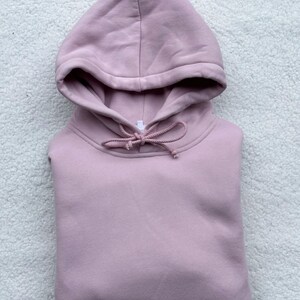 May include: A pale pink hooded sweatshirt with a drawstring.