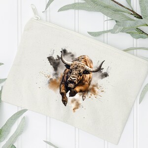 May include: A white canvas zippered pouch with a brown bull charging through a cloud of dust. The bull has a fierce expression and is depicted in a watercolor style.