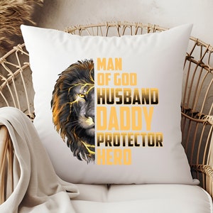 May include: White throw pillow with a black and gold lion graphic and the text "Man of God, Husband, Daddy, Protector, Hero".