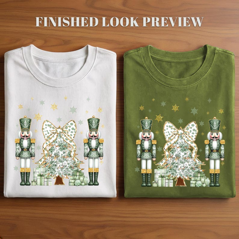 May include: A white t-shirt and an olive green t-shirt, each featuring a graphic of two nutcrackers flanking a Christmas tree with a large bow and wrapped gifts, accented by gold and green snowflakes and the text FINISHED LOOK PREVIEW.