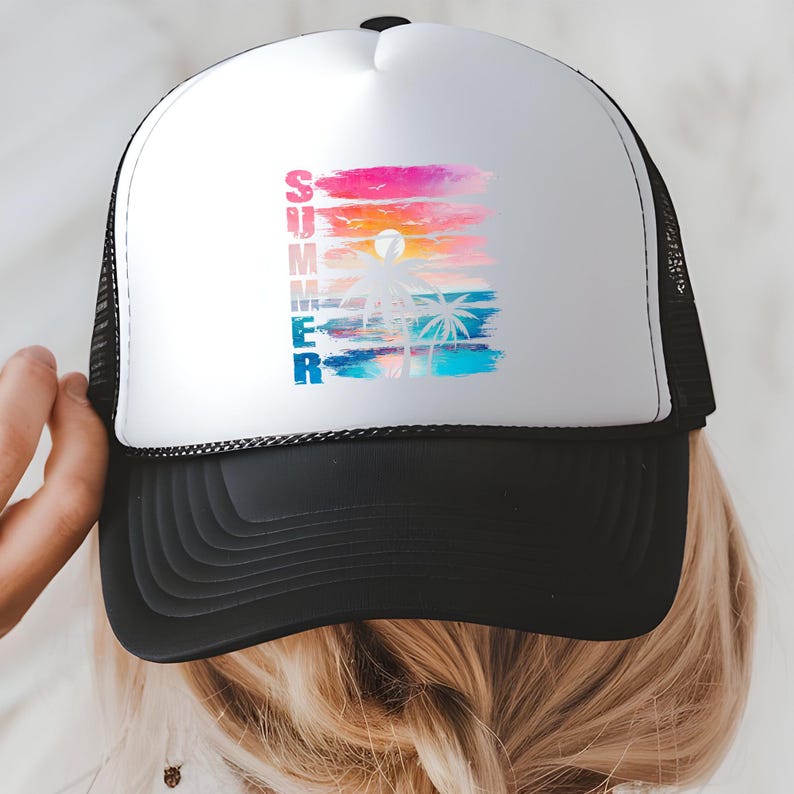 A person is wearing a white baseball cap with a colorful graphic design on it, depicting a sunset with palm trees.