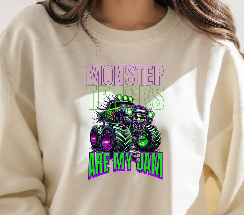 May include: A white sweatshirt featuring a green and purple monster truck graphic with the text "Monster Trucks Are My Jam".