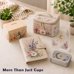 Puede incluir: Un conjunto que incluye una hucha de madera, un neceser beige, una agenda floral, un letrero de acr&iacute;lico transparente con dise&ntilde;o de luna y sol, y una caja de metal, decorados con motivos florales y el texto More Than Just Cups.