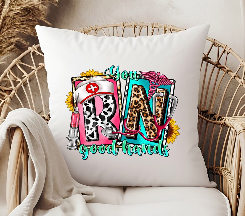May include: White throw pillow with a colorful graphic design featuring the letters "RN" with a stethoscope, a syringe, a sunflower, and the text "You good hands".