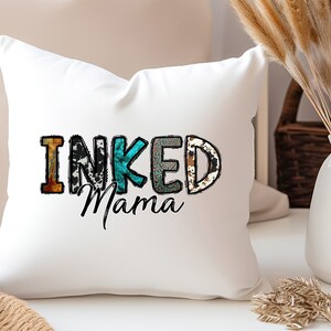 以下が含まれることがあります： パッチワークのデザインでカラフルな文字で「INKED Mama」と書かれた白いクッション