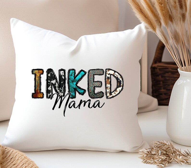 以下が含まれることがあります： パッチワークのデザインでカラフルな文字で「INKED Mama」と書かれた白いクッション
