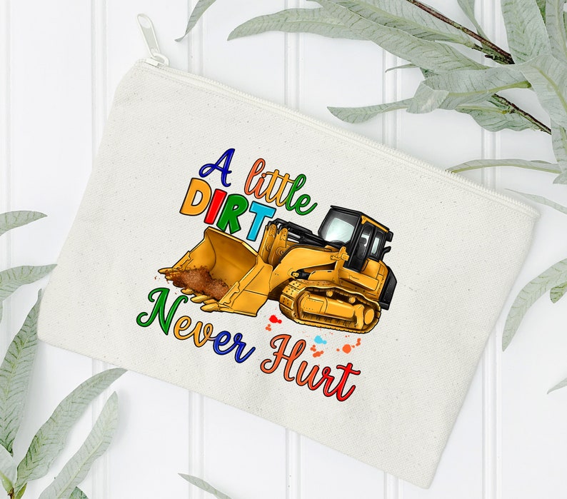 May include: A white canvas zippered pouch with a colorful graphic of a yellow excavator with the text "A little dirt never hurt".