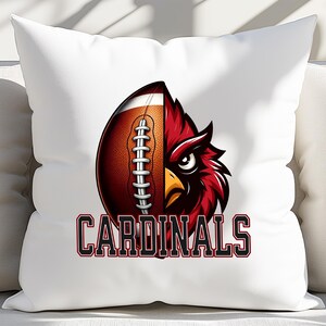 Puede incluir: Almohada blanca con un dise&ntilde;o de cardenal rojo y f&uacute;tbol. El bal&oacute;n de f&uacute;tbol est&aacute; dividido por la mitad, con la cabeza del cardenal ocupando la otra mitad. El texto "CARDINALS" est&aacute; impreso debajo de la imagen.