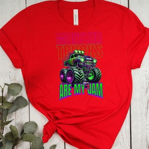 May include: Red t-shirt featuring a green and black monster truck graphic with the text "Monster Trucks Are My Jam".