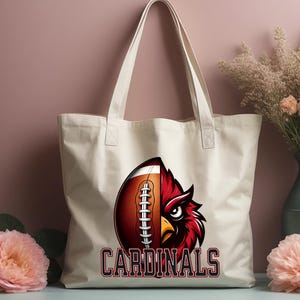 Puede incluir: Bolsa de tela blanca con un gr&aacute;fico de f&uacute;tbol rojo y marr&oacute;n y el texto "CARDINALS".