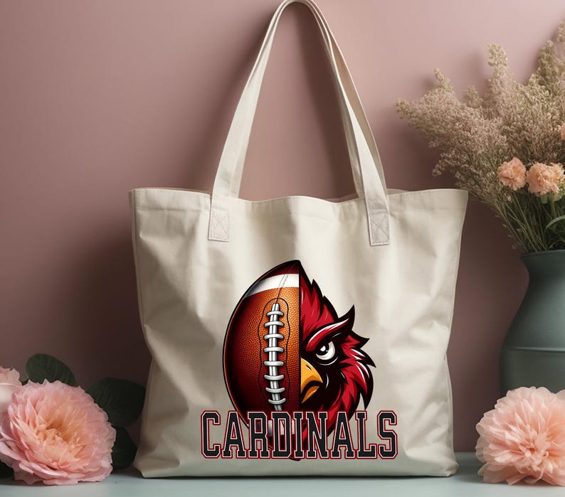 Puede incluir: Bolsa de tela blanca con un gr&aacute;fico de f&uacute;tbol rojo y marr&oacute;n y el texto "CARDINALS".