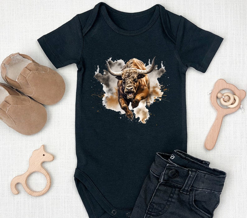 May include: Black baby onesie with a brown bull graphic. The bull is charging with its horns forward and mouth open. The bull is on a white background with brown splatters.