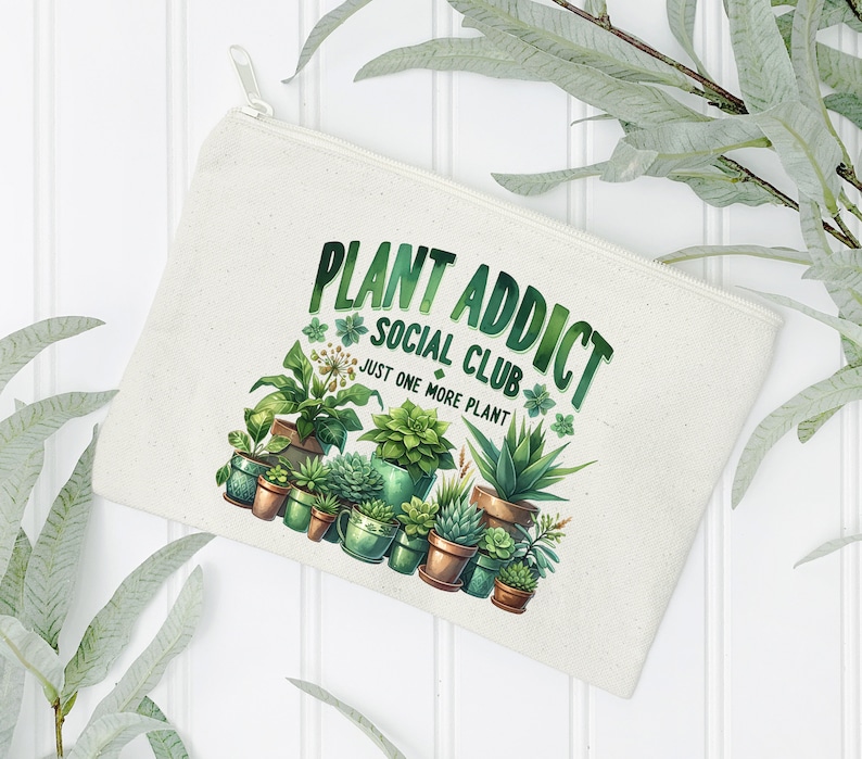 May include: A white canvas zippered pouch with the text "Plant Addict Social Club Just One More Plant" and a colourful illustration of various potted plants.