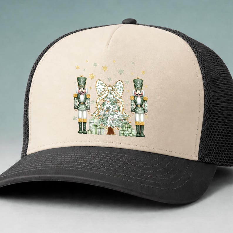 May include: A beige and black trucker hat featuring a graphic print of two green nutcrackers standing on either side of a decorated Christmas tree with a large bow on top and several wrapped gift boxes at the base, accented by gold stars.