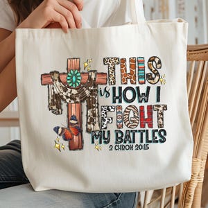 a person holding a white tote bag with a colorful and artistic design on it.