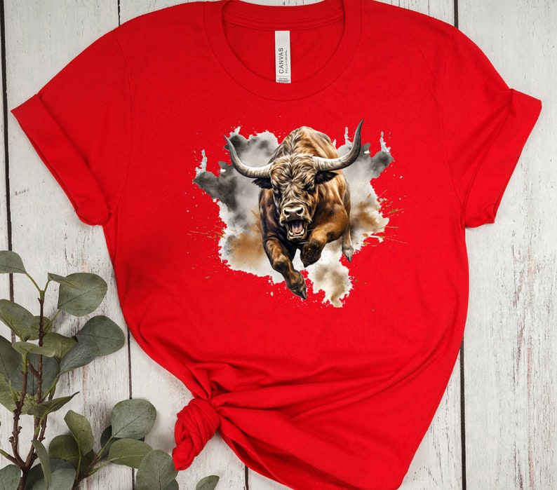 May include: Red t-shirt with a graphic of a brown bull charging through a cloud of dust and paint splatters.