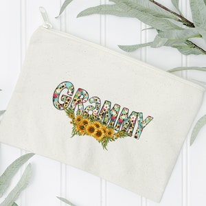 Op de afbeelding: Een witte canvas ritszak met het woord "GRAMMY" bedrukt in gele letters met een bloemen- en luipaardprint.
