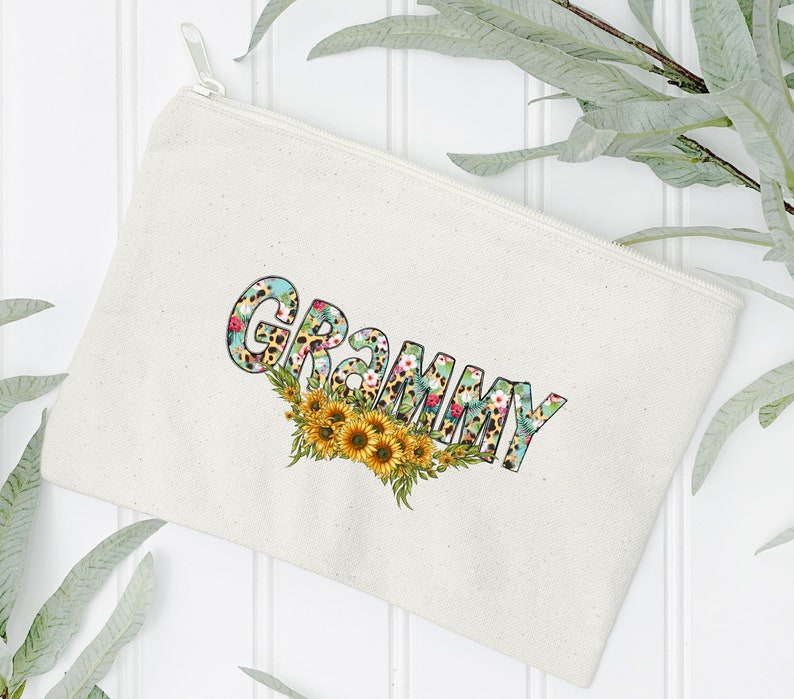 Op de afbeelding: Een witte canvas ritszak met het woord "GRAMMY" bedrukt in gele letters met een bloemen- en luipaardprint.