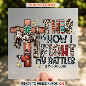 The image is a hand holding a printed piece of paper with a colorful and artistic design featuring a cross, butterflies, and various text elements.