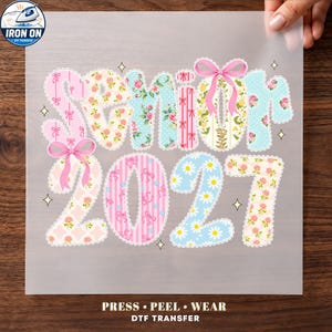 May include: A DTF transfer sheet featuring the text Senior 2027 in a scalloped-edge font. The letters and numbers are decorated with various floral, polka dot, and striped patterns in pink, blue, and yellow, accented by two pink bows.