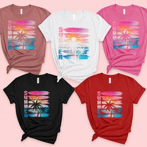 a collection of five t-shirts with a beach-themed design, featuring palm trees and a sunset.
