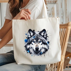 May include: A white canvas tote bag with a watercolor illustration of a wolf's face. The wolf has blue eyes and is surrounded by blue paint splatters.