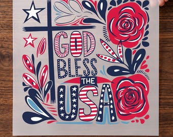 May include: A DTF transfer sheet featuring the text GOD BLESS THE USA in red, white, and blue. The design includes a dark blue cross, two large red roses, and stars. The text PRESS PEEL WEAR DTF TRANSFER is printed at the bottom of the sheet.