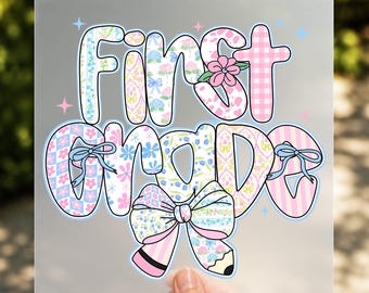 May include: A decorative iron-on transfer with the words "First Grade" in a whimsical font. The letters are adorned with floral, gingham, and striped patterns in pastel colors, with a large bow and pencil design.