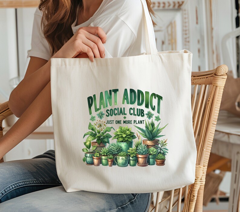 May include: A white canvas tote bag with the text "Plant Addict Social Club" and the phrase "Just One More Plant". The bag features a colourful illustration of various potted plants.